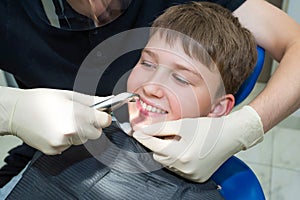 A child patientÃ¢â¬â¢s portrait and a child dentistÃ¢â¬â¢s hands with dental forceps, a close-up photo